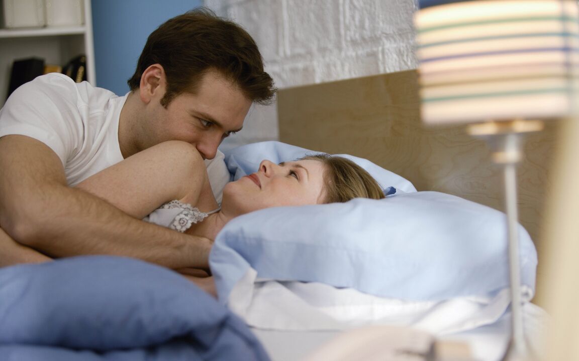 A woman in bed with a man with an enlarged penis